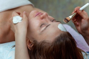 Spa, tatil köyü, güzellik ve sağlık konsepti - güzellik salonunda yüz bakımı gören güzel bir kadın