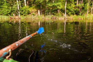 Kürek kürek dalgalanmalar ile yeşil göl kenarında suda hareket satır tekneden closeup