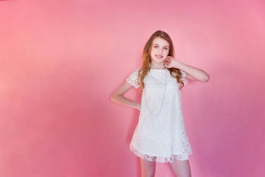 Mutlu genç kız gülümsüyor. Beyaz elbise ayakta pembe renkli pastel trendy modern moda pin-up arka plan üzerinde giyen portre portre genç mutlu pozitif kadın. Avrupa kadın. Olumlu insan duygu yüz ifadesi beden dili