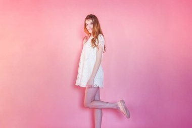 Mutlu genç kız gülümsüyor. Beyaz elbise ayakta pembe renkli pastel trendy modern moda pin-up arka plan üzerinde giyen portre portre genç mutlu pozitif kadın. Avrupa kadın. Olumlu insan duygu yüz ifadesi beden dili
