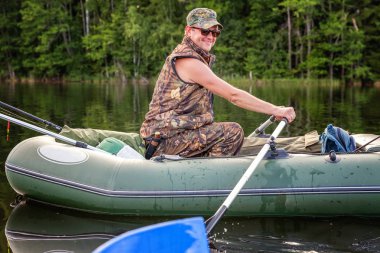 Bir balıkçı bir teknede güzel bir göle balık tutma