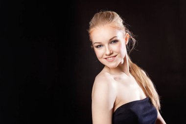 Siyah arka planda uzun sarı saçlı güzel bir mankenin yakın plan portresi.