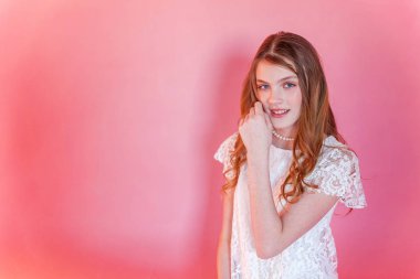 Mutlu genç kız gülümsüyor. Beyaz elbise ayakta pembe renkli pastel trendy modern moda pin-up arka plan üzerinde giyen portre portre genç mutlu pozitif kadın. Avrupa kadın. Olumlu insan duygu yüz ifadesi beden dili