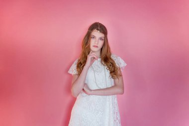 Mutlu genç kız gülümsüyor. Beyaz elbise ayakta pembe renkli pastel trendy modern moda pin-up arka plan üzerinde giyen portre portre genç mutlu pozitif kadın. Avrupa kadın. Olumlu insan duygu yüz ifadesi beden dili