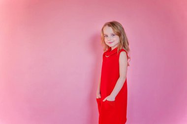 Küçük şirin tatlı gülümseyen kız pembe renkli pastel trendy modern moda pin-up arka plan üzerinde kırmızı elbise ayakta