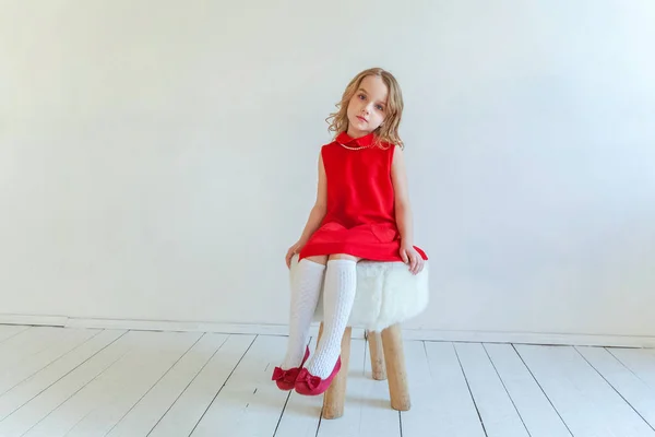 Doce Menina Feliz Vestido Vermelho Sentado Cadeira Contra Fundo Parede — Fotografia de Stock