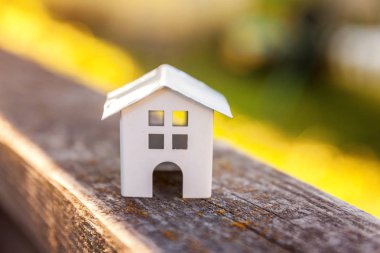Minyatür beyaz oyuncak model ev, arka planda, yeşil arkaplanın yanında. Eco Village, soyut çevre geçmişi. Gayrimenkul ipoteği sigortası rüya ev ekolojisi kavramı