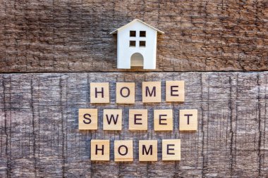 Yazıt ahşap zemin üzerinde Home Sweet Home harf kelime ile minyatür oyuncak model evi. Eko Köyü, çevre arka plan. Emlak mortgage Emlak sigorta ekoloji kavramı