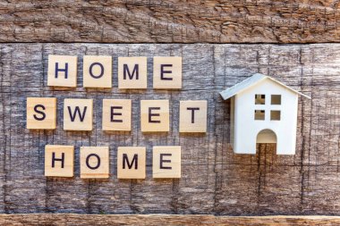 Yazıt ahşap zemin üzerinde Home Sweet Home harf kelime ile minyatür oyuncak model evi. Eko Köyü, çevre arka plan. Emlak mortgage Emlak sigorta ekoloji kavramı