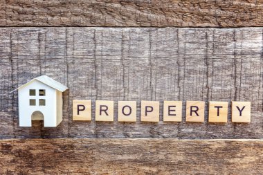 Yazıt ahşap zemin üzerinde özellik harf kelime ile minyatür oyuncak model evi. Eko Köyü, çevre arka plan. Emlak mortgage Emlak sigorta tatlı ev ekoloji kavramı