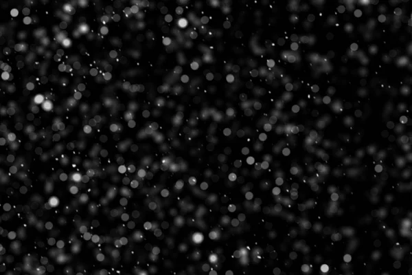 Falling down real white snowflakes on black background. Isolated snowfall calm snow minimalistic design element. Snowstorm texture. Bokeh lights on black background, shot of flying snowflakes in air