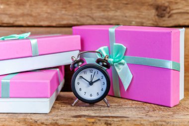Çalar saat ve Hediyelik kutu pembe kağıt sarılı. Noel ve yeni yıl hediye eski püskü rustik ahşap zemin üzerine dekore edilmiştir. Christmas Doğum günü Sevgililer günü kutlama romantik mevcut konsept süre