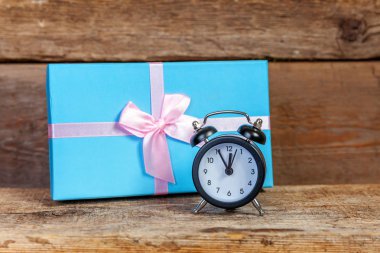 Çalar saat ve Hediyelik kutu mavi kağıt sarılı. Noel ve yeni yıl hediye eski püskü rustik ahşap zemin üzerine dekore edilmiştir. Christmas Doğum günü Sevgililer günü kutlama hediyesi romantik kavramı için zaman