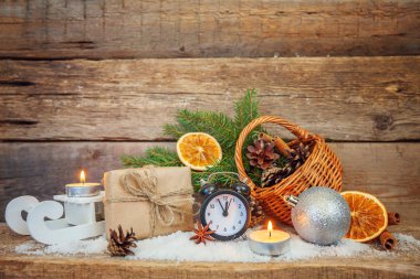 Yılbaşı yeni yıl kompozisyon kış nesneleri kutusunu köknar şube sepet çam kozalakları topları kızak mum çalar saat eski püskü rustik ahşap arka plan üzerinde hediye. Xmas tatil Aralık dekorasyon kopyalama alanı