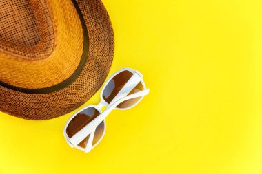 Düz sarı renkli şık modern moda arka plan üzerinde retro şapka ve güneş gözlüğü yatırın. Tatil seyahat yaz hafta sonu deniz macera seyahat kavramı
