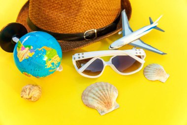 Düz şapka, küre, uçak, güneş gözlüğü ve kabuk sarı renkli şık modern moda zemin üzerine yatırın. Tatil seyahat yaz hafta sonu deniz macera seyahat kavramı
