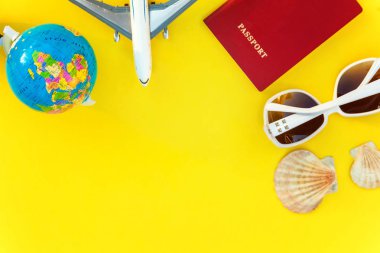 Uçak, pasaport, dünya, güneş gözlüğü ve kabuk üzerinde sarı renkli şık modern moda arka plan düz yatırın. Tatil seyahat yaz hafta sonu deniz macera seyahat kavramı