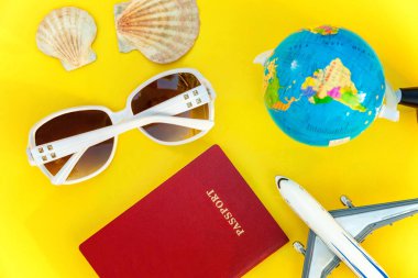 Uçak, pasaport, dünya, güneş gözlüğü ve kabuk üzerinde sarı renkli şık modern moda arka plan düz yatırın. Tatil seyahat yaz hafta sonu deniz macera seyahat kavramı