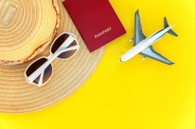 Düz şapka, uçak, pasaport ve güneş gözlüğü sarı renkli şık modern moda zemin üzerine yatırın. Tatil seyahat yaz hafta sonu deniz macera seyahat kavramı