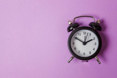 İki Yataklı çan vintage klasik çalar saat göl kenarında mor menekşe pastel renkli arka plan üzerinde zil. Yaşam süresi saat sabah gece iyi dinlen uyanık kavramı uyandır. Düz yatıyordu üstten görünüm kopya alanı