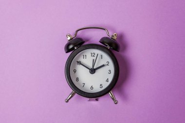 İki Yataklı çan vintage klasik çalar saat göl kenarında mor menekşe pastel renkli arka plan üzerinde zil. Yaşam süresi saat sabah gece iyi dinlen uyanık kavramı uyandır. Düz yatıyordu üstten görünüm kopya alanı