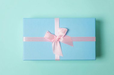 Küçük hediye kutusu, pembe pastel renkli trendy geometrik arka plan izole mavi kağıt sarılı. Yılbaşı yeni yıl Doğum günü Sevgililer günü kutlama hediyesi romantik kavramı