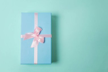 Küçük hediye kutusu, pembe pastel renkli trendy geometrik arka plan izole mavi kağıt sarılı. Yılbaşı yeni yıl Doğum günü Sevgililer günü kutlama hediyesi romantik kavramı
