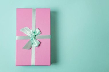 Küçük hediye kutusu pembe kağıt mavi pastel renkli trendy geometrik arka plan üzerinde izole sarılmış. Yılbaşı yeni yıl Doğum günü Sevgililer günü kutlama hediyesi romantik kavramı