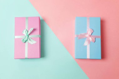 Küçük hediye kutusu mavi ve pembe pastel renkli trendy geometrik arka plan üzerinde izole pembe ve mavi kağıt sarılı. Yılbaşı yeni yıl Doğum günü Sevgililer günü kutlama hediyesi romantik kavramı