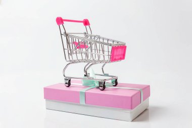 Küçük süpermarket bakkal itme cart pembe hediye kutusu beyaz arka plan üzerinde izole ile oyuncak alışveriş için. Satılık Alışveriş Merkezi Pazar dükkanı tüketici kavramı satın. Kopya alanı