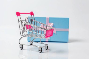 Küçük süpermarket bakkal itme sepeti beyaz arka plan üzerinde izole mavi hediye kutusu ile oyuncak alışveriş için. Satılık Alışveriş Merkezi Pazar dükkanı tüketici kavramı satın. Kopya alanı