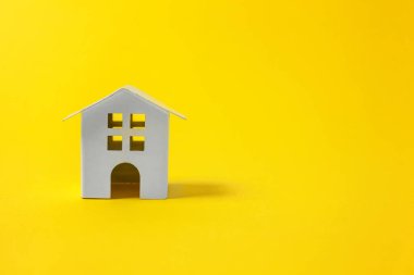 Sade bir şekilde izole sarı renkli şık modern moda arka plan üzerinde beyaz minyatür oyuncak ev tasarım. Mortgage Emlak sigorta rüya ev concept. Kopya alanı