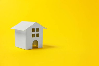 Sade bir şekilde izole sarı renkli şık modern moda arka plan üzerinde beyaz minyatür oyuncak ev tasarım. Mortgage Emlak sigorta rüya ev concept. Kopya alanı