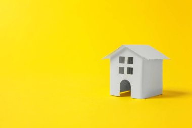Sade bir şekilde izole sarı renkli şık modern moda arka plan üzerinde beyaz minyatür oyuncak ev tasarım. Mortgage Emlak sigorta rüya ev concept. Kopya alanı