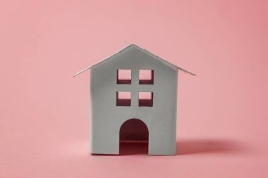 Sadece pembe pastel renkli şık arka plan üzerinde izole minyatür beyaz oyuncak ev tasarım. Mortgage Emlak sigorta rüya ev concept. Kopya alanı