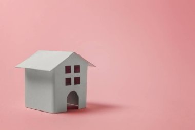Sadece pembe pastel renkli şık arka plan üzerinde izole minyatür beyaz oyuncak ev tasarım. Mortgage Emlak sigorta rüya ev concept. Kopya alanı