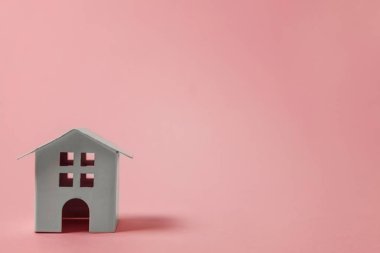 Sadece pembe pastel renkli şık arka plan üzerinde izole minyatür beyaz oyuncak ev tasarım. Mortgage Emlak sigorta rüya ev concept. Kopya alanı