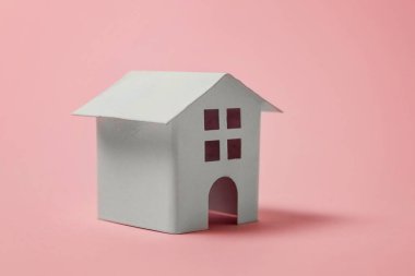 Sadece pembe pastel renkli şık arka plan üzerinde izole minyatür beyaz oyuncak ev tasarım. Mortgage Emlak sigorta rüya ev concept. Kopya alanı