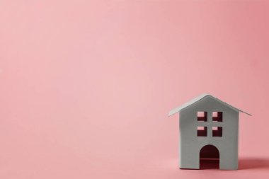 Sadece pembe pastel renkli şık arka plan üzerinde izole minyatür beyaz oyuncak ev tasarım. Mortgage Emlak sigorta rüya ev concept. Kopya alanı