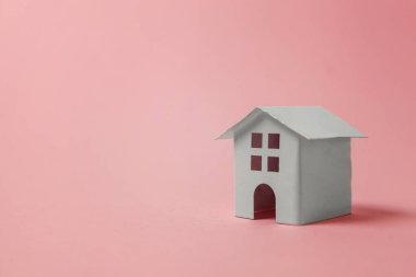 Sadece pembe pastel renkli şık arka plan üzerinde izole minyatür beyaz oyuncak ev tasarım. Mortgage Emlak sigorta rüya ev concept. Kopya alanı