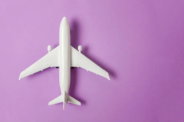 简单平坦的平面设计微型玩具模型平面上的紫罗兰色柔和的彩色纸新潮的背景 乘坐飞机度假暑假海险旅行旅游票务旅游概念 — 图库照片