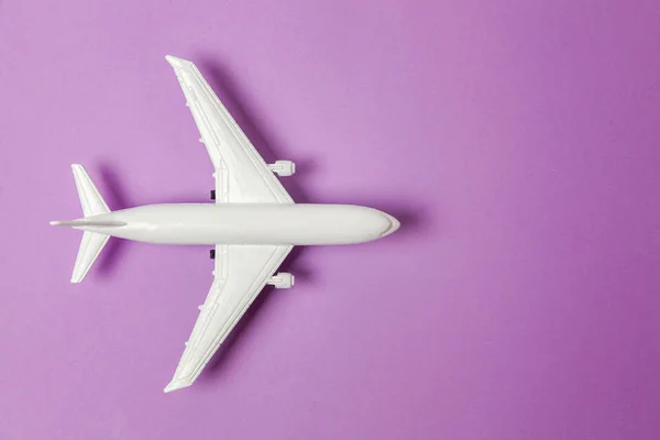 简单平坦的平面设计微型玩具模型平面上的紫罗兰色柔和的彩色纸新潮的背景 乘坐飞机度假暑假海险旅行旅游票务旅游概念 — 图库照片