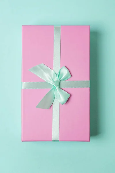 小さなギフト ボックスはラップ青パステル調のカラフルなトレンディな幾何学的な背景に分離されたピンクのペーパーです クリスマス正月誕生日バレンタインのお祝いは ロマンチックな概念を提示します — ストック写真