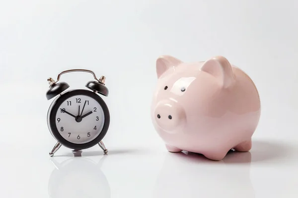 Pink piggy bank and classic alarm clock isolated on white background. Saving time investment budget wealth business retirement, financial, money, banking concept. Copy space