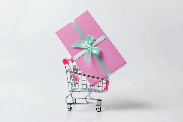 小超市杂货店推车购物玩具与粉红色礼品盒隔离在白色背景 销售购买商场市场商铺消费者的概念 复制空间 — 图库照片