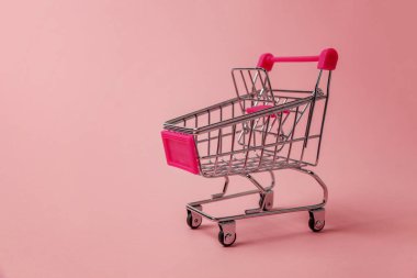 Küçük süpermarket bakkal itme cart pembe pastel renkli kağıt trendy arka plan üzerinde izole tekerlekli oyuncak alışveriş için. Satılık Alışveriş Merkezi Pazar dükkanı tüketici kavramı satın. Kopya alanı