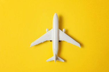 Sade bir şekilde yatıyordu tasarım minyatür oyuncak model uçak sarı renkli kağıt trendy arka plan üzerinde düz. Uçak tatil yaz hafta sonu deniz macera seyahat yolculuk bilet Tur kavramı ile seyahat