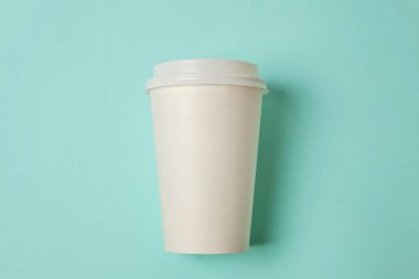 Sade bir şekilde yatıyordu tasarım kağıt kahve Kupası mavi pastel renkli şık arka plan üzerinde düz. Paket servisi olan restoran içki kabı. Günaydın uyanık kavramı uyandır. İçki mockup şablonu. Üstten görünüm kopya alanı