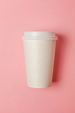 Sade bir şekilde yatıyordu tasarım kağıt kahve Kupası pembe pastel renkli şık arka plan üzerinde düz. Paket servisi olan restoran içki kabı. Günaydın uyanık kavramı uyandır. İçki mockup şablonu. Üstten görünüm kopya alanı