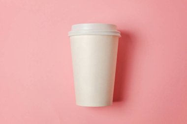 Sade bir şekilde yatıyordu tasarım kağıt kahve Kupası pembe pastel renkli şık arka plan üzerinde düz. Paket servisi olan restoran içki kabı. Günaydın uyanık kavramı uyandır. İçki mockup şablonu. Üstten görünüm kopya alanı